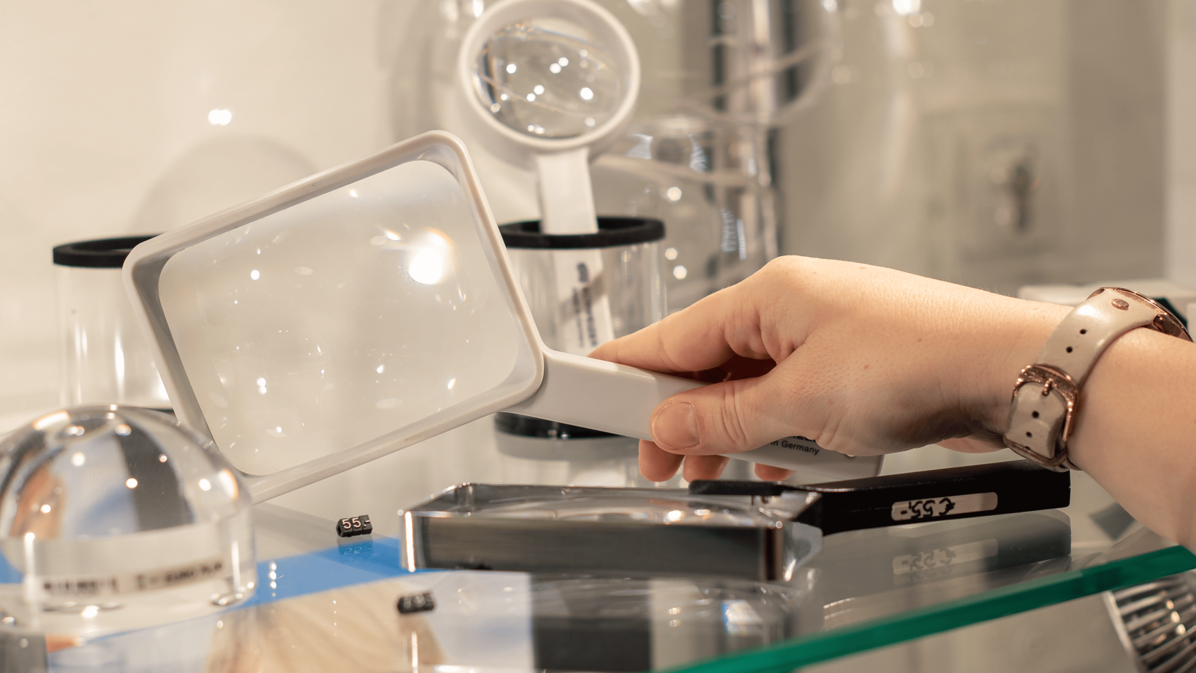 Eine Hand nimmt eine Lupe aus dem Regal mit anderen Lupen.